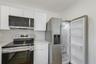 Kitchen featuring high-gloss white flat-panel cabinetry, stone-finish countertops, stainless steel microwave, stainless steel slide-in range, and stai