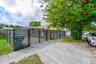 Horizontal slat metal perimeter fencing with integrated dual-swing entry gate and mature landscape canopy