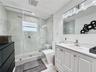 Bathroom featuring a frameless glass-enclosed shower with large-format wall tile and hexagonal floor tile, a white vanity cabinet with an integrated s