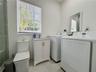 Bathroom featuring a floor-mounted toilet, vanity with a stone-finish countertop and integrated sink, wall-mounted mirror, and tile flooring