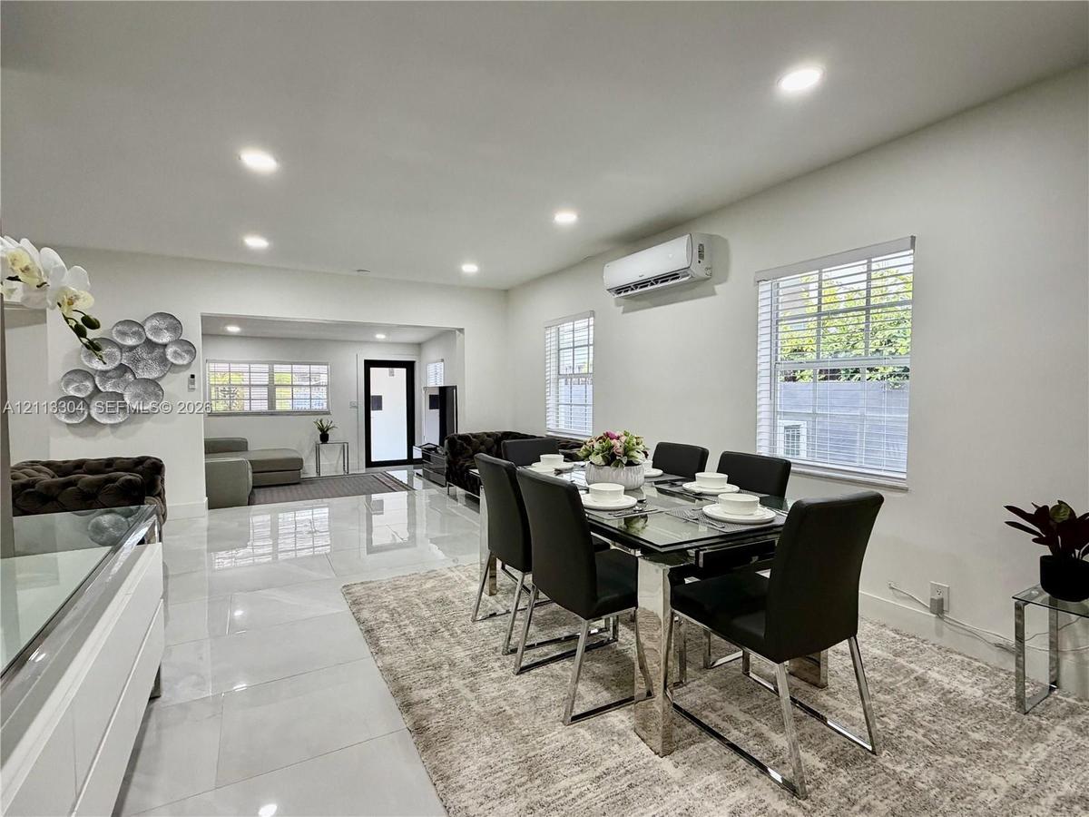 Polished tile flooring, recessed lighting, wall-mounted climate control unit, and multiple windows with white horizontal blinds
