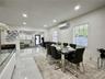 Polished tile flooring, recessed lighting, wall-mounted climate control unit, and multiple windows with white horizontal blinds