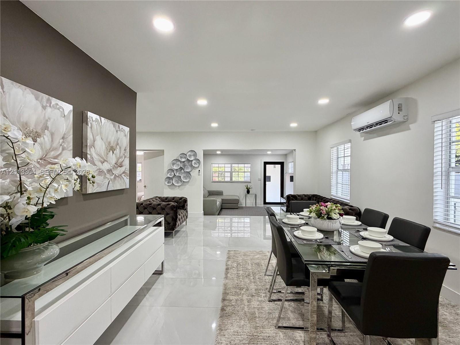 Open-concept space featuring polished tile flooring, recessed lighting, wall-mounted climate control unit, and crisp neutral wall tones