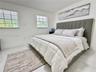 Neutral-toned interior featuring large-format tile flooring and two windows with adjustable horizontal blinds