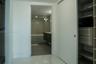 Walk-in closet with built-in wood-finish shelving and drawer storage, featuring large-format tile flooring and a sliding door