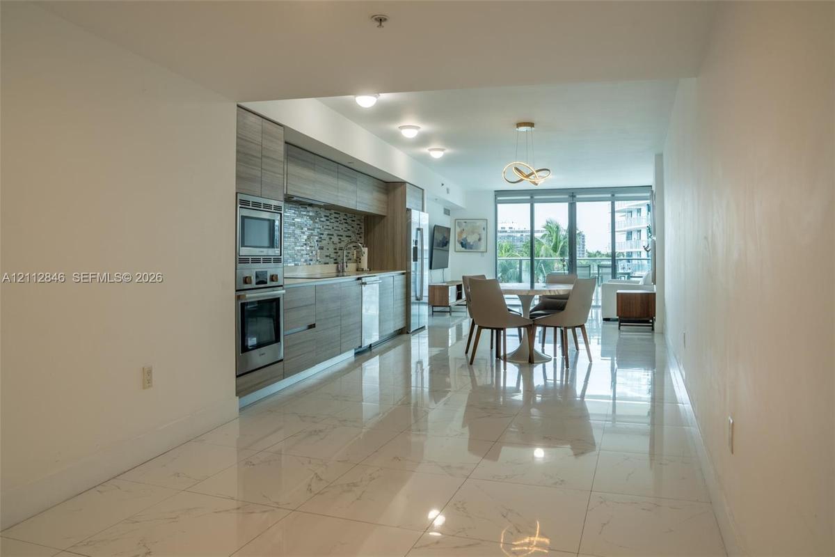 Kitchen featuring horizontal-grain cabinetry, stainless steel wall oven and microwave, mosaic tile backsplash, and floor-to-ceiling glass panel window