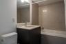 Bathroom featuring a dark wood-finish vanity, integrated sink with light-toned solid surface countertop, rectangular wall mirror, and a bathtub enclos