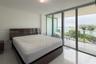 Floor-to-ceiling sliding glass doors, white tile flooring, and private balcony with metal railing and water scenery