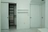Walk-in closet featuring custom wood-finish shelving and built-in drawers, set against polished white tile flooring