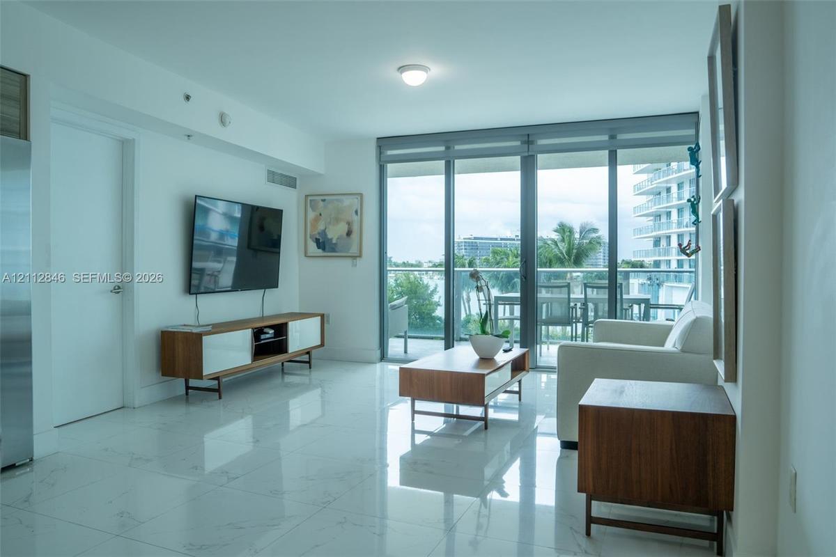 Polished stone flooring, expansive floor-to-ceiling glass sliding doors, and a private balcony