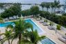 Waterfront pool and spa area featuring natural stone decking, integrated palm tree landscaping, and perimeter glass railing