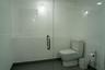 Glass-enclosed shower with white panel wall surrounds, chrome handle hardware, and large-format tile flooring