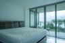 Floor-to-ceiling glass sliding doors with metallic framing, large-format tile flooring, and a private balcony featuring a glass panel railing