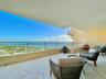 Covered balcony featuring stone flooring and a metallic railing overlooking the ocean and coastline