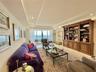 Living area featuring floor-to-ceiling glass sliding doors, built-in wooden cabinetry with shelving, recessed ceiling lighting, and tile flooring