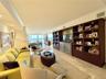Large living area featuring polished stone flooring, extensive built-in floor-to-ceiling dark wood shelving, recessed lighting, and floor-to-ceiling w