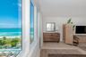 Floor-to-ceiling windows, light-toned wood-finish flooring, and ocean horizon backdrop