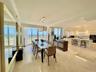 Open-concept living space featuring polished tile flooring, floor-to-ceiling glass sliding doors, custom white cabinetry, a built-in kitchen island wi