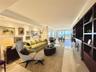 Open-concept living space featuring large-format polished stone flooring, custom floor-to-ceiling dark wood built-in cabinetry, recessed perimeter lig