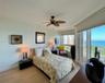 Floor-to-ceiling windows, light wood-finish flooring, ceiling fan, and coastal horizon backdrop