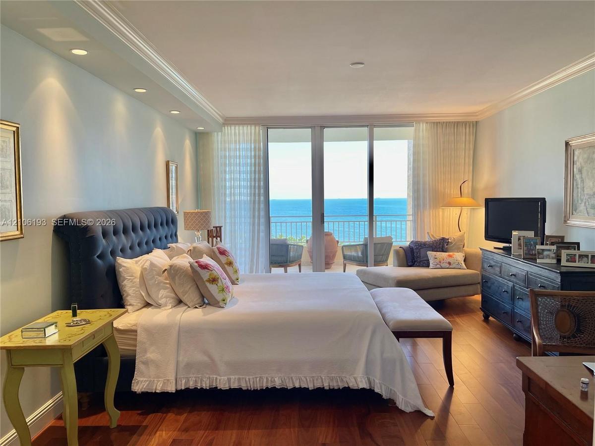 Bedroom featuring wood-finish flooring, recessed lighting, crown molding, and floor-to-ceiling glass sliding doors opening to a balcony with ocean exp