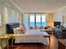 Bedroom featuring wood-finish flooring, recessed lighting, crown molding, and floor-to-ceiling glass sliding doors opening to a balcony with ocean exp