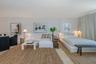 Expansive open-concept room featuring light-toned flooring, neutral wall finishes, and floor-to-ceiling curtain treatments