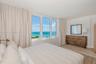 Expansive window wall with ocean and coastal horizon scenery, light-toned wood-finish flooring, and neutral wall palette