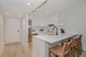 Kitchen featuring flat-panel cabinetry, light-toned countertops, a matte black high-arch faucet, integrated stainless steel appliances, and wood-finis