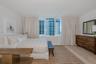 Floor-to-ceiling windows with neutral drapery and light-tone wood-finish flooring