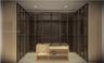Custom dressing area featuring floor-to-ceiling cabinetry with glass-panel doors, integrated shelving, and a central built-in island with a countertop