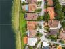 Aerial perspective of waterfront property featuring extensive shoreline access, a tiled roofline, and paved driveway
