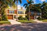 Modern dual-structure exterior featuring wood-finished siding, stone masonry cladding, integrated garage doors, floor-to-ceiling windows, and second-l