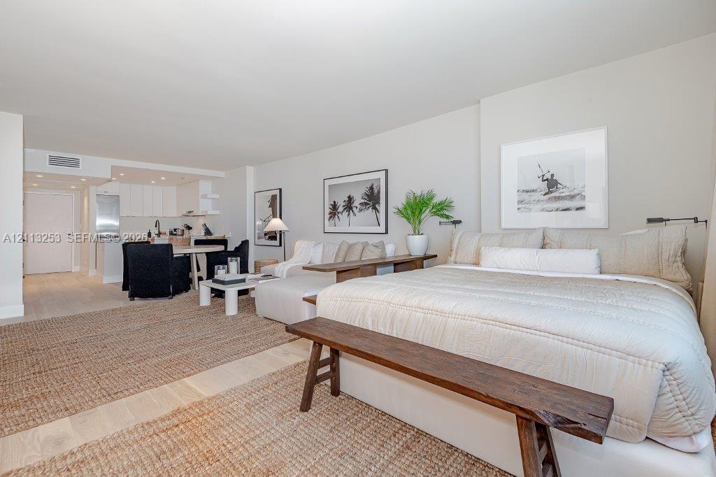 Open-concept interior featuring light-toned flooring, recessed ceiling lighting, and a kitchen area with white cabinetry and stainless steel appliance