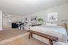 Open-concept interior featuring light-toned flooring, recessed ceiling lighting, and a kitchen area with white cabinetry and stainless steel appliance