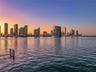 Waterfront property featuring a private dock and direct water access, showcasing a expansive cityscape backdrop at dusk