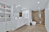 Bathroom featuring a floating double vanity with rectangular sinks, a floor-to-ceiling white built-in storage cabinet, large-format tile flooring, and