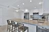 Kitchen featuring high-gloss white cabinetry, a neutral stone-surface peninsula, stainless steel appliances, recessed ceiling lighting, and tile floor