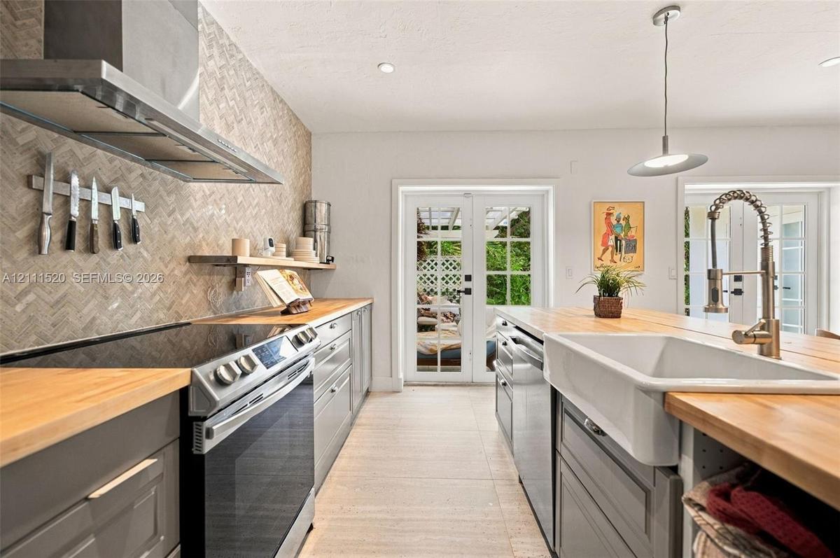 Kitchen featuring butcher block countertops, a farmhouse-style apron sink, a herringbone-patterned tile backsplash, stainless steel appliances, and Fr