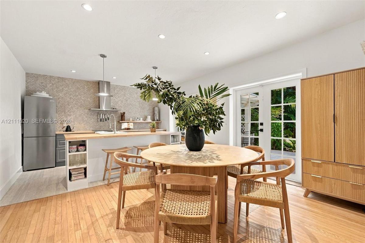 Kitchen featuring a breakfast bar with wood countertop, herringbone-patterned tile backsplash, stainless steel range hood, and recessed lighting, fini