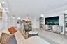 Open-concept living space featuring high-gloss white cabinetry, polished tile flooring, recessed ceiling lighting, and a breakfast bar