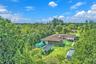 Expansive lot featuring mature trees, a multi-section roofline, and extensive open green space