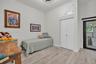 Room featuring wood-finish flooring, high ceilings, custom built-in upper storage, double-door closet, and glass-paneled exterior door with black fram