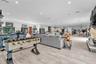 Open-concept interior featuring light wood-finish flooring, recessed lighting, a stone-accented fireplace hearth, and extensive custom cabinetry
