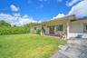 Single-story residence featuring a covered front porch, light-toned exterior finish, multi-pane entry door, concrete driveway, and expansive lawn area