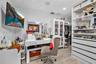 Walk-in closet featuring white custom built-in cabinetry, glass-front display shelving, integrated drawer units, and wood-finish flooring