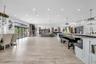 Open-concept interior featuring light wood-finish flooring, recessed lighting, stone-clad fireplace, and multi-panel folding glass doors