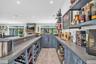 Custom built-in bar featuring stained wood cabinetry, stone countertops, integrated wine storage, and floating wall-mounted shelving with recessed lig