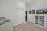 Wood-finish flooring, vaulted ceiling, dual-door closet, and upper storage cabinet with X-detail inlay