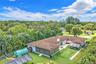 Expansive backyard featuring artificial turf, a masonry chimney, and perimeter landscaping